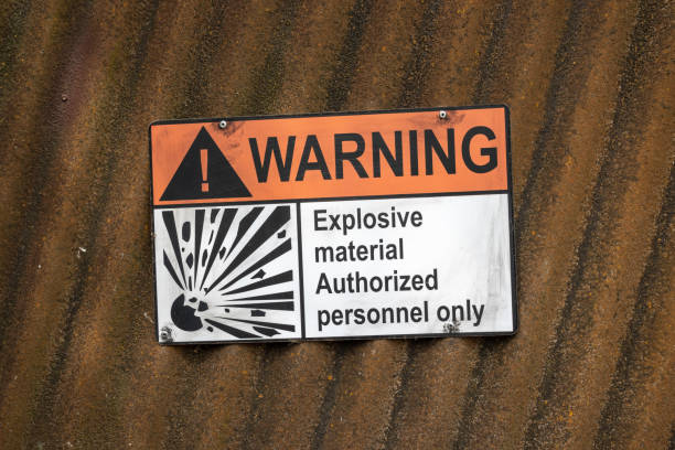 Warning sign on a corrugated iron wall with the inscription: explosive material authorized personnel only Warning sign on a corrugated iron wall with the inscription: explosive material authorized personnel only explosive stock pictures, royalty-free photos & images