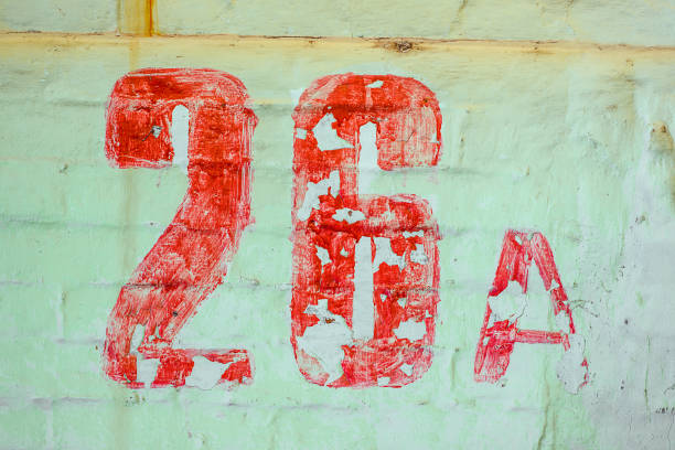 istock Number Twenty Six Drawn By Red paint On Whitewashed Brick Wall. Shabby Building With Damaged cracked Plaster 1141419168
