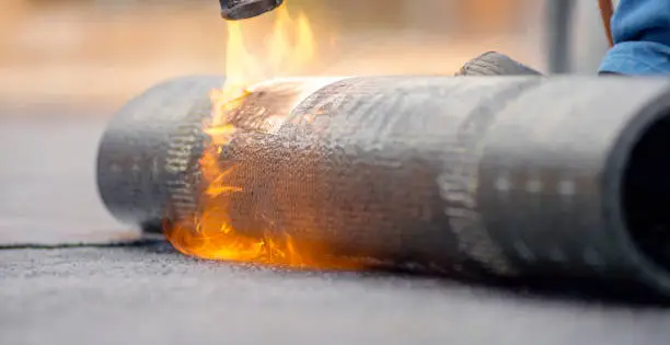 Close-up of heating and melting of bitumen rolls.