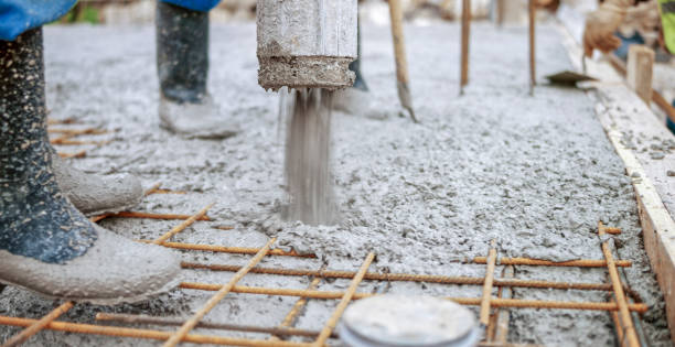 Construction workers pouring cement on roof Manual workers pouring cement through pipe on roof. rebar production stock pictures, royalty-free photos & images