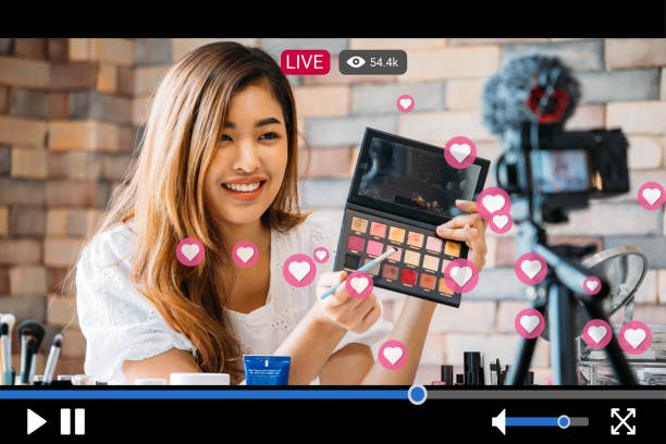 Woman does makeup while recording live stream with video player interface Young beautiful woman recording live stream video for makeup and cosmetics business purpose online with video player interface and full of positive feedbacks influencer stock pictures, royalty-free photos & images