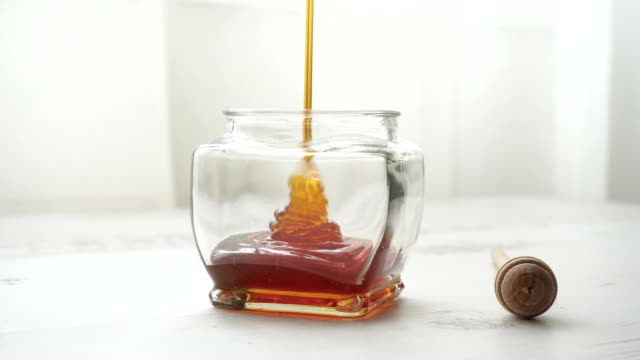 Pouring honey into jar of honey