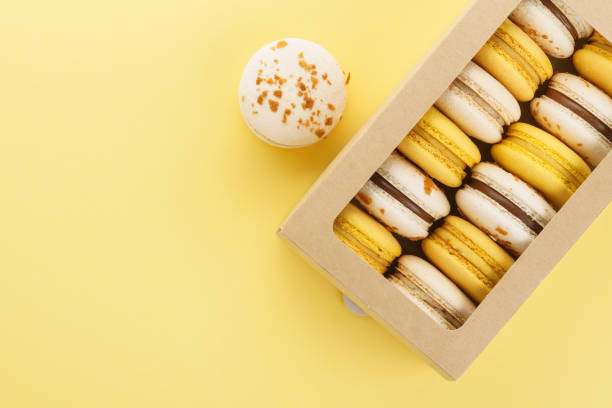 istock Colorful macarons in a gift box on yellow background. 1141425175