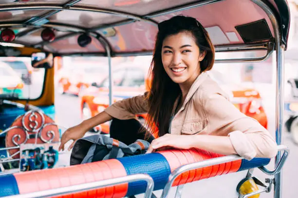 Young Asian female tourist woman exploring Bangkok, Thailand with local tuk tuk taxi and sightseeing the city