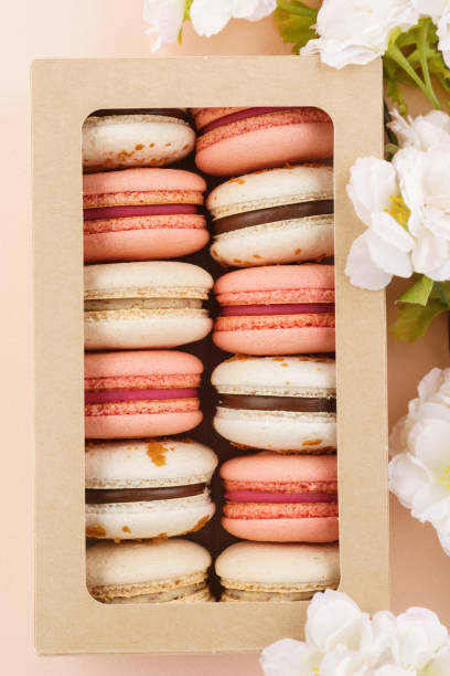 istock Macarons in a box and flowers on pink background. 1141425956