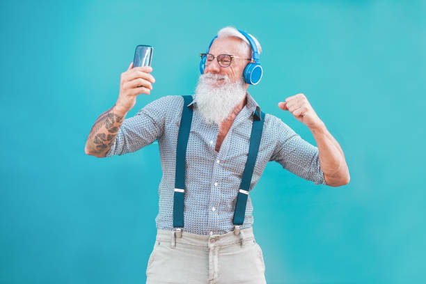istock Senior hipster man using smartphone app for creating playlist music - Trendy tattoo guy having fun with mobile phone technology - Tech and joyful elderly lifestyle concept - Focus on his face 1141427212