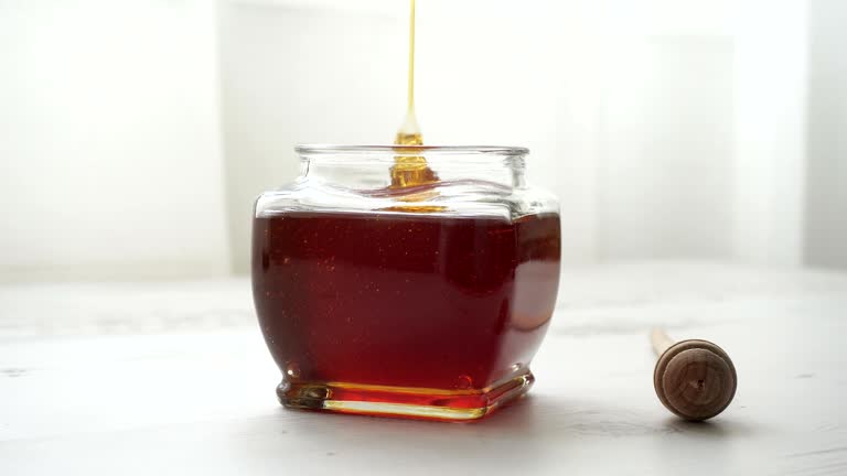 Pouring honey into jar of honey