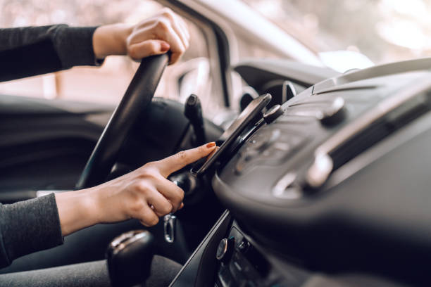 primo tempo della donna incinta caucasica alla guida dell'auto e accensione del gps sullo smartphone. altra mano sul volante. - automotive accessories foto e immagini stock