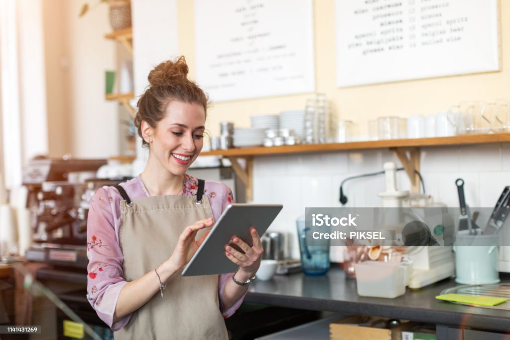 Young woman using digital tablet in coffee shop Small Business Stock Photo