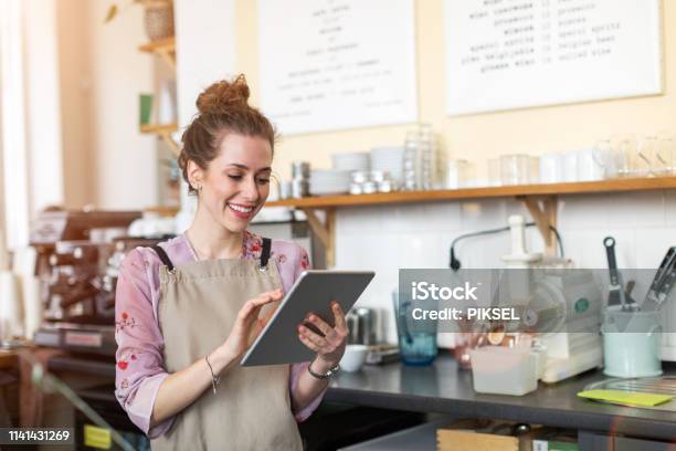 Young Woman Using Digital Tablet In Coffee Shop Stock Photo - Download Image Now - Small Business, Owner, Digital Tablet