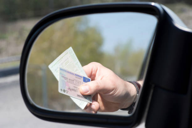 A Man shows Driver's License and Vehicle License during a Check A man shows driver's license and vehicle registration at a check driver's license stock pictures, royalty-free photos & images