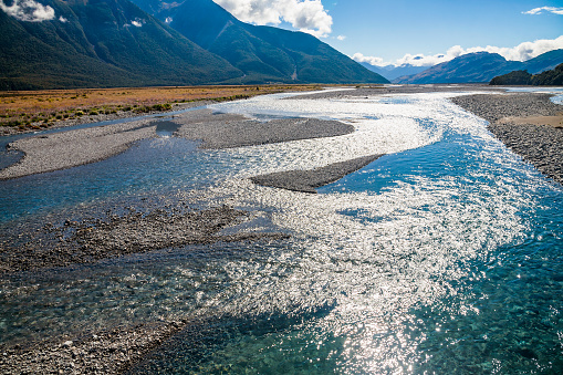 Sun reflecting in Waimakariri or Courtenay River, shallow braided river that flows from the Southern Alps across the Canterbury Plains to the Pacific Ocean in the South Island of New Zealand