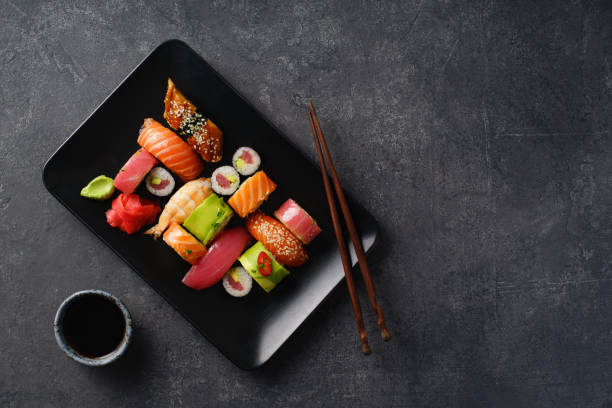 overhead image of variety of sushi and rolls served on a plate. shrimp, unagi, crab, salmon and tuna - susi imagens e fotografias de stock