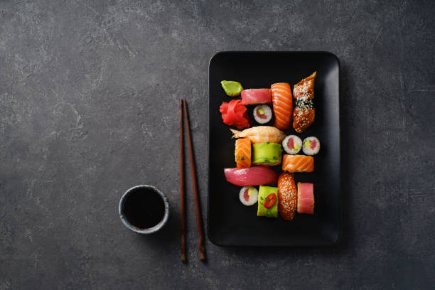 image aérienne de la variété des sushis et des rouleaux servis sur une assiette. crevettes, unagi, crabe, saumon et thon - susi photos et images de collection