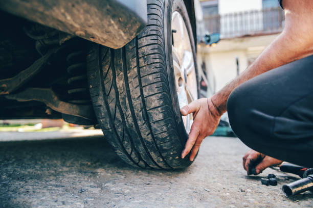 istock Close up of auto mechanic changing tire while crouching at workshop. 1141440156