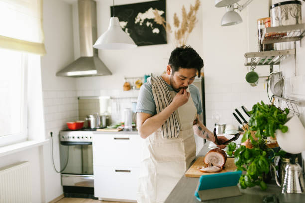 Asian man making chashu pork with the help of digital cookbook