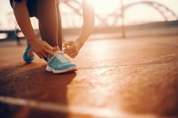 Close up of sporty caucasian woman kneeling and tying shoelace on court in the morning. Sometimes the best runs come on days you didn’t feel like running.