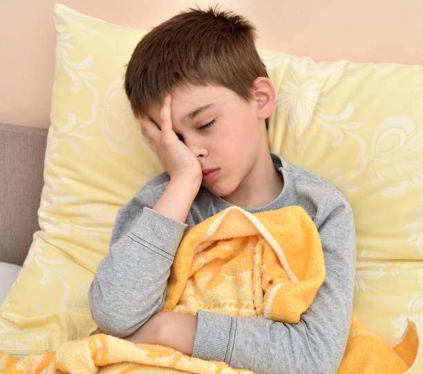 istock Young boy sitting in bed with headache 1141443793