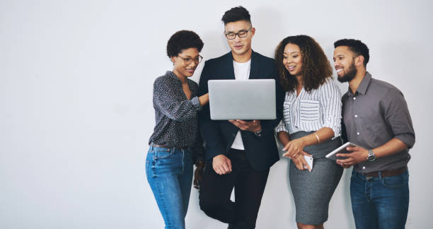 Taking business into the online domain Studio shot of a group of businesspeople using a laptop together against a white background public domain images stock pictures, royalty-free photos & images