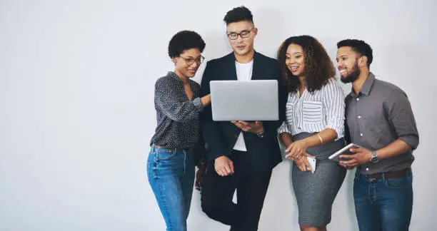 Studio shot of a group of businesspeople using a laptop together against a white background