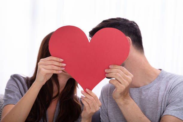 istock Couple Hiding Behind Heart Shape 1141447278