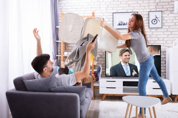 istock Woman Throwing Dirty Clothes On Lazy Husband 1141447307