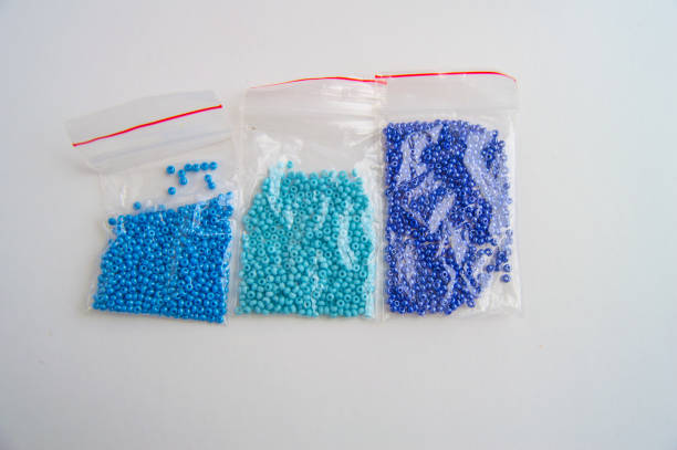 Set of three plastic bags with blue glass beads with gradient color on white background, beaded embroidery accessories