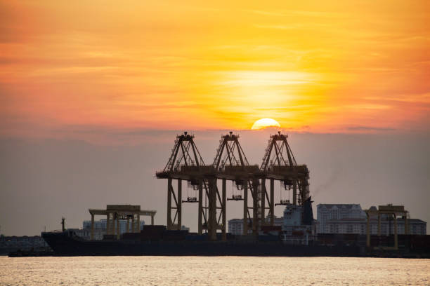 istock Crane for shipping container carrier with sunrise background 1141447626