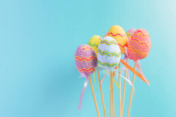 pascua coloridos huevos decorados se destacan en un palillos sobre fondo azul claro. concepto mínimo de pascua. feliz pascua tarjeta con copia espacio para el texto. - easter holiday feast day yellow fotografías e imágenes de stock