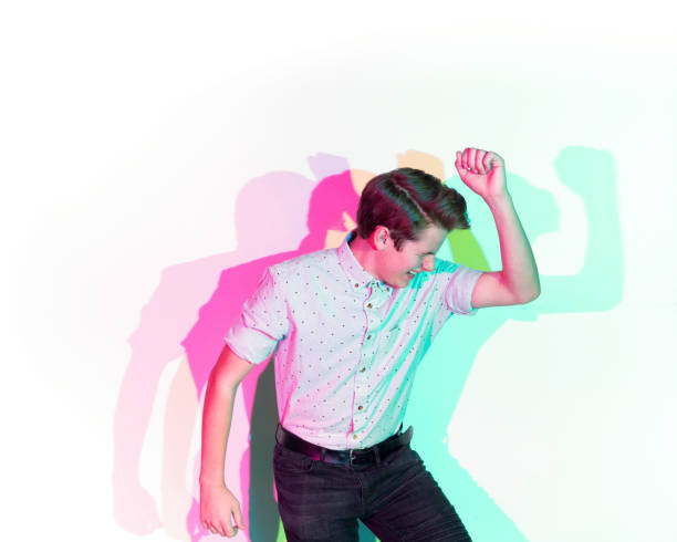 istock Handsome young man standing against white wall with colorful shadows 1141450903