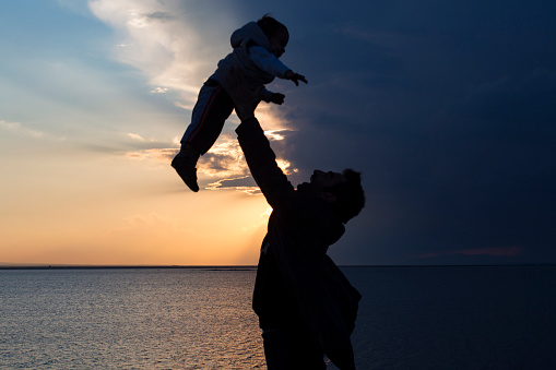 gün batımı manzarasında baba ve bebeği arasındaki eğlenceli görüntü