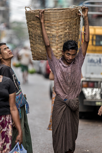 Yangon, Myanmar - 22th November, 2017 : A basket porter is walking along Yangon Street.