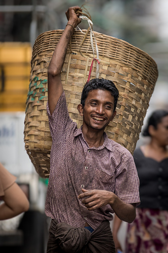 Yangon, Myanmar - 22th November, 2017 : A smiling basket porter is walking along Yangon Street.