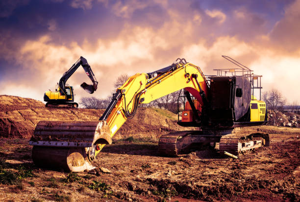 istock Digger working against a dramatic sky with another digger on the hill in the background 1141453593