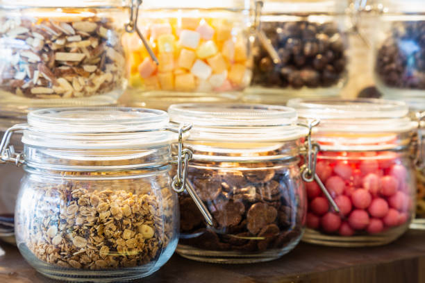Close up multicolor topping ice cream with bubble gum, chocolate serial, almond, marshmallow in glass Jar on wooden shelf.