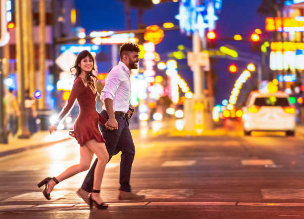 Couple enjoying Las  Vegas nightlife A couple holding hands as they run across the street at a crosswalk in Las Vegas at night. the strip las vegas stock pictures, royalty-free photos & images