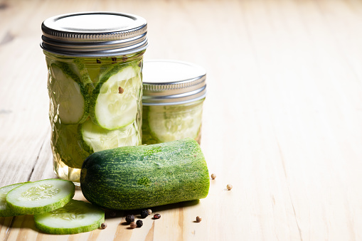 Pickled cucumbers with spices on wooden background