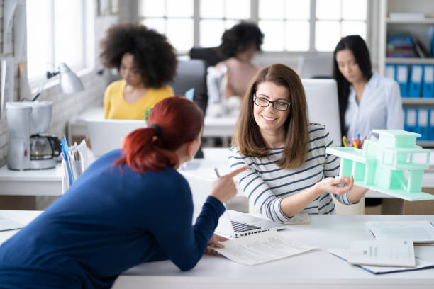 istock Smiling woman with eyeglasses presenting 3D model in modern office 1141456814