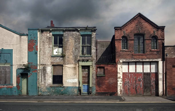 derelict abandoned houses and buildings on a deserted residential street with boarded up windows and decaying crumbling walls against a grey cloudy sky derelict abandoned houses and buildings on a deserted residential street with boarded up windows and decaying crumbling walls against a grey cloudy sky hull house stock pictures, royalty-free photos & images
