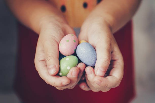 istock Little girl hands holding easter eggs painted color on hand 1141459292