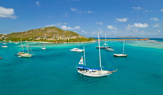 sailing yachts anchoring in the turquoise waters behind the reef of Union Island, St Vincent and Grenadines, West Indies