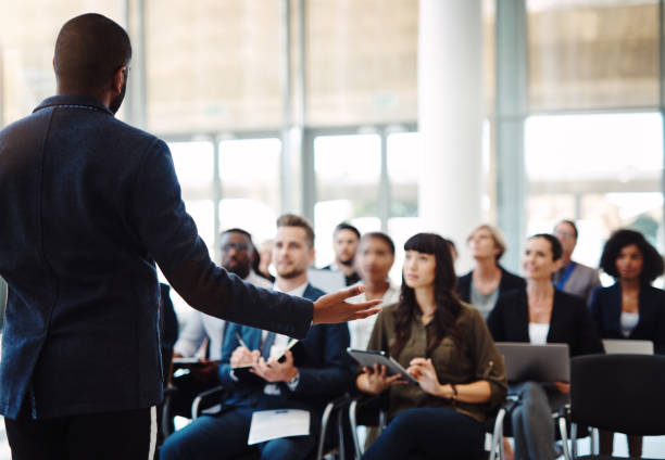 Keeping his audience engaged Shot of a businessman delivering a speech during a conference keynote speech stock pictures, royalty-free photos & images