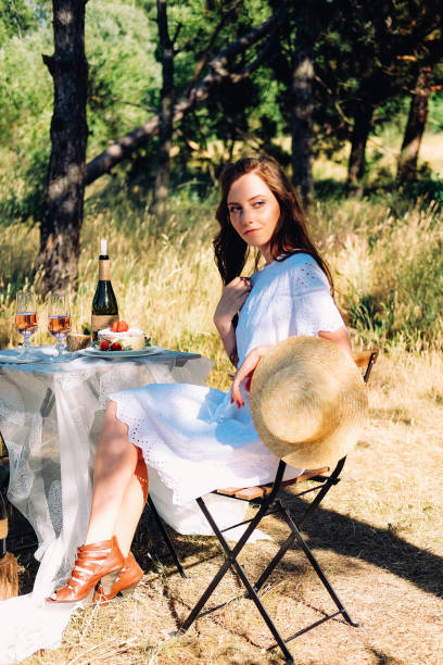 istock Summer engagement picnic. Young bride sitting at the table served for dinner. 1141464728
