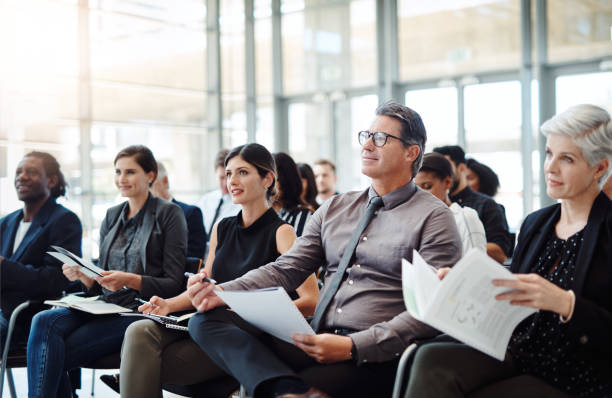 Get your notes out and let the learning begin Shot of a group of businesspeople attending a conference group of people men mature adult serious stock pictures, royalty-free photos & images