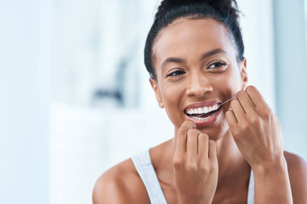 It's not clean until you floss it Cropped shot of an attractive young woman flossing her teeth in the bathroom at home dental floss stock pictures, royalty-free photos & images