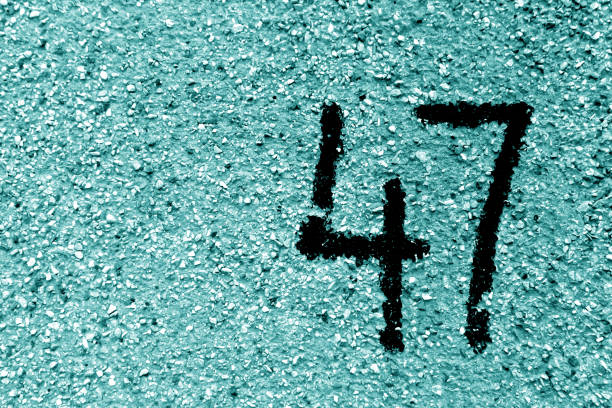 Number 47 on cement wall in stencil in cyan tone