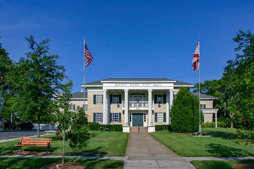 Mount Dora City Hall and Landscaped Grounds with State and US Flags flying under a clear blue sky