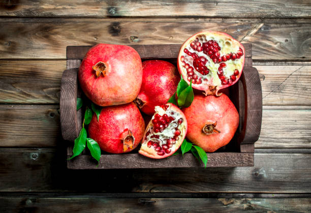 istock Ripe pomegranates with leaves in the box. 1141481117