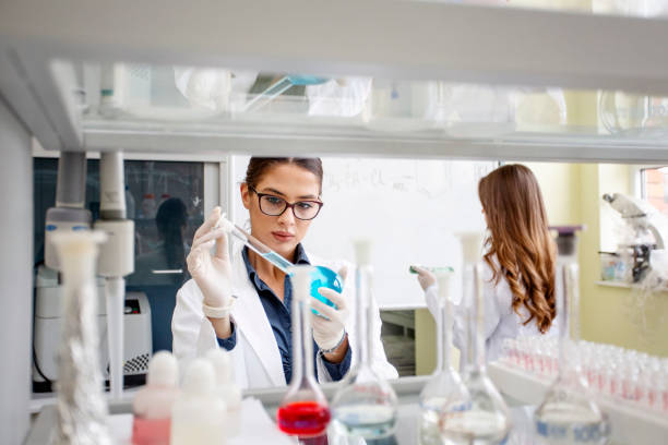 istock Two young woman in laboratory one of them prepare for analyze while second write on white board at background 1141481496