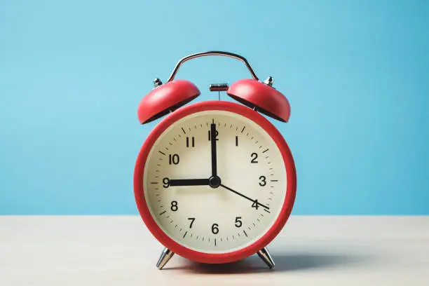 Photo of Red vintage alarm clocks on wooden table and light blue background wall